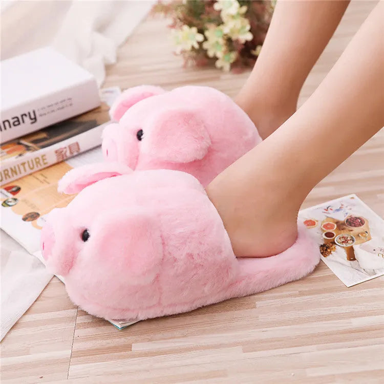 Pink pig-shaped plush floor slippers with a soft, textured surface and cushioned sole.