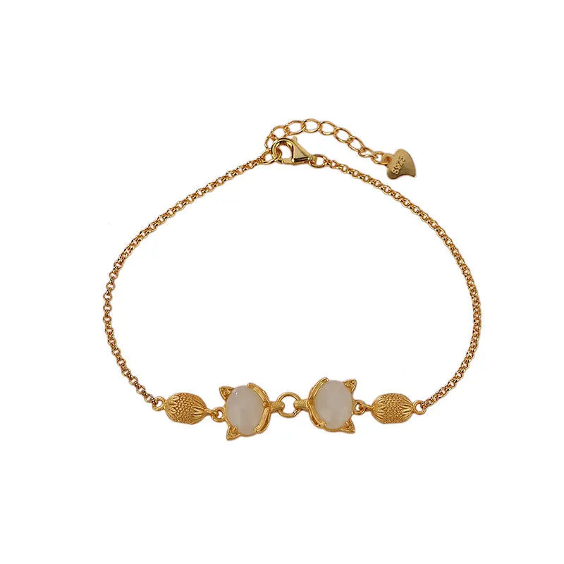 Close-up of a sterling silver fox charm bracelet with a Hetian jade stone on a model's wrist.