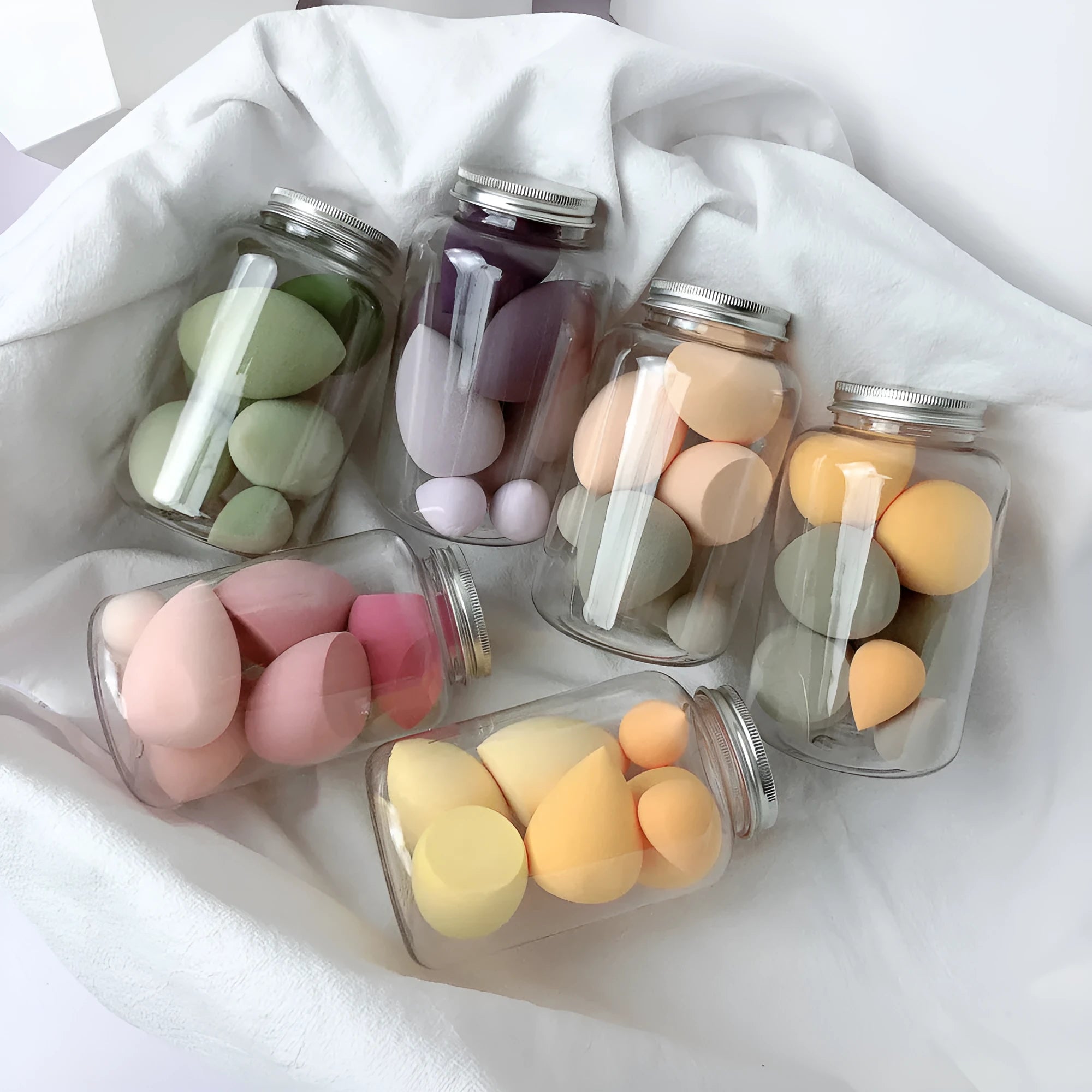 Set of 7 makeup sponge eggs in various colours inside transparent jar with multiple cut shapes