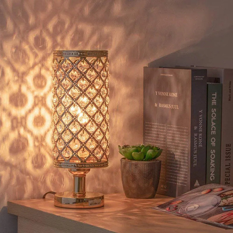 Modern crystal table lamp with hollow-carved design, metal base, gold finish, push button switch, on bedside table