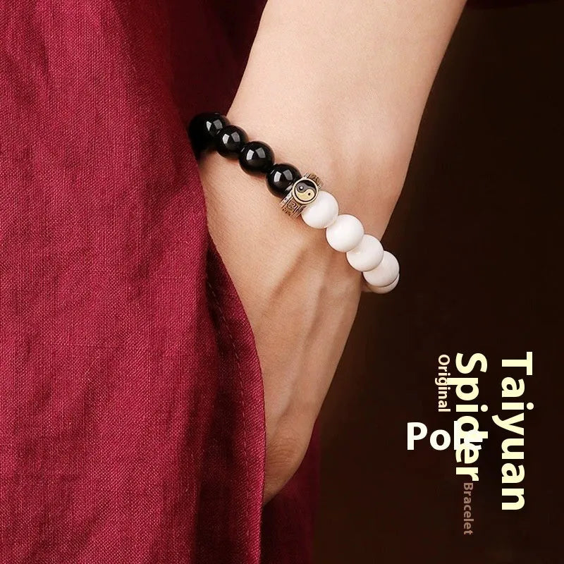 Black and white Taiji symbol bracelet made from obsidian beads with engraved mantra.