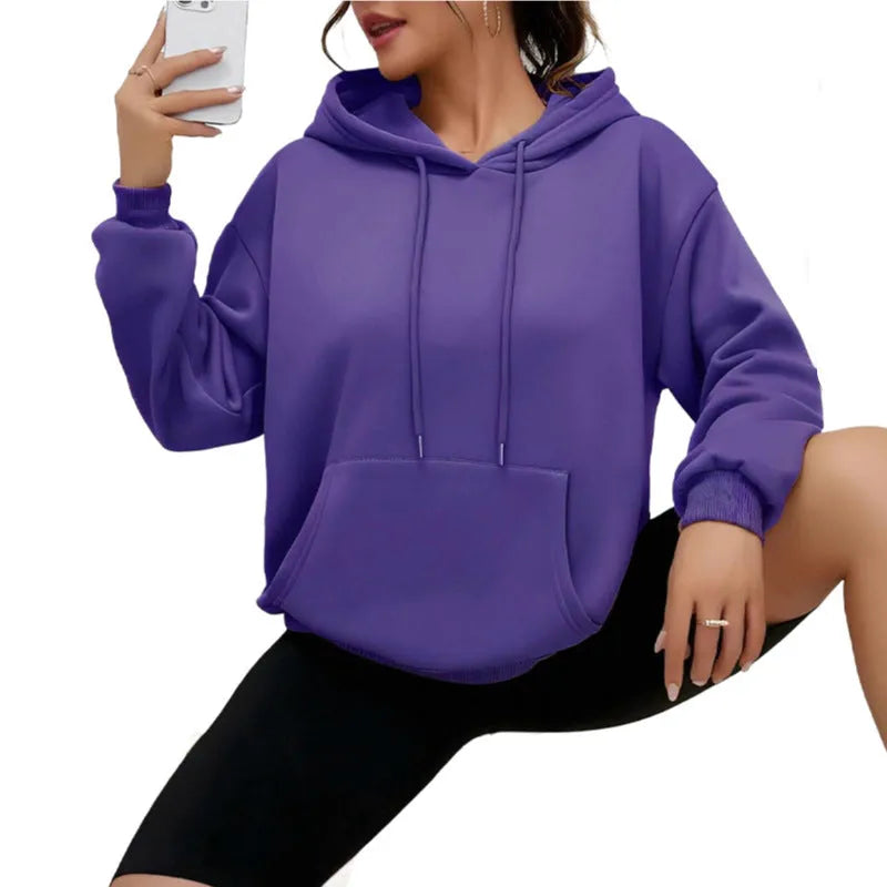Women's loose grey sweatshirt with a front pocket and drawstring waist, worn with jeans.