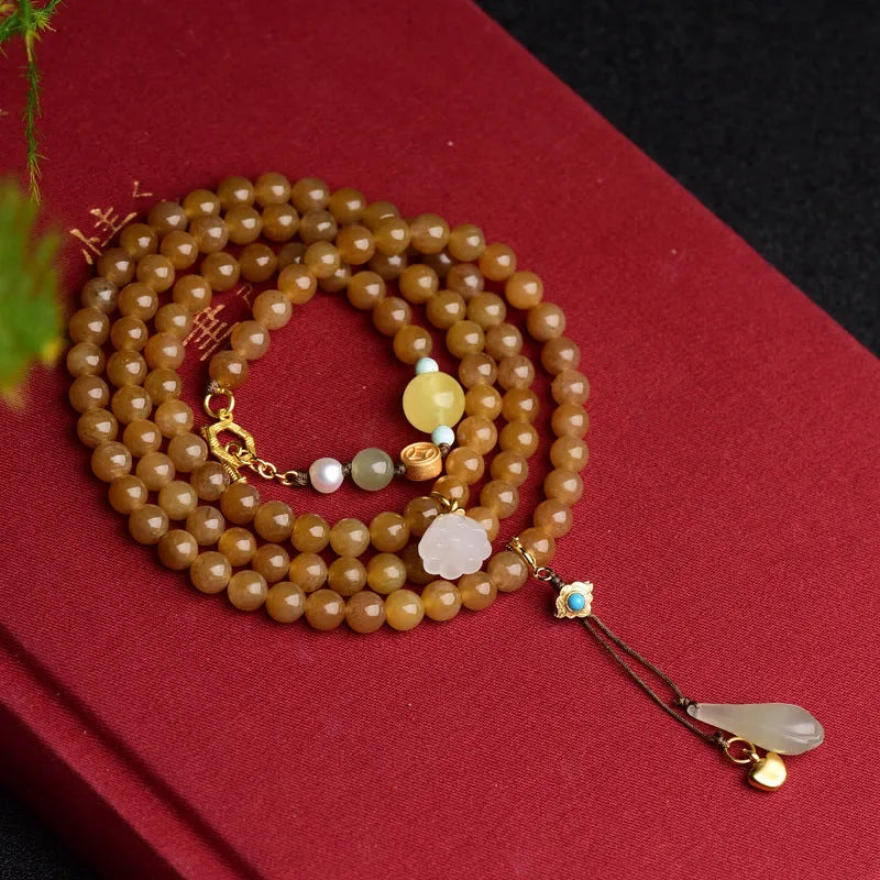 Close-up of a women's green jade bracelet with 6mm beads, beeswax, and leaf charms on a wrist.
