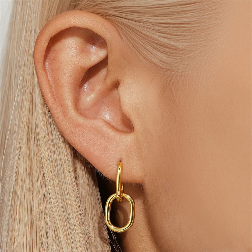 Geometric brass earclip earrings with a gold electroplated finish and round design details.