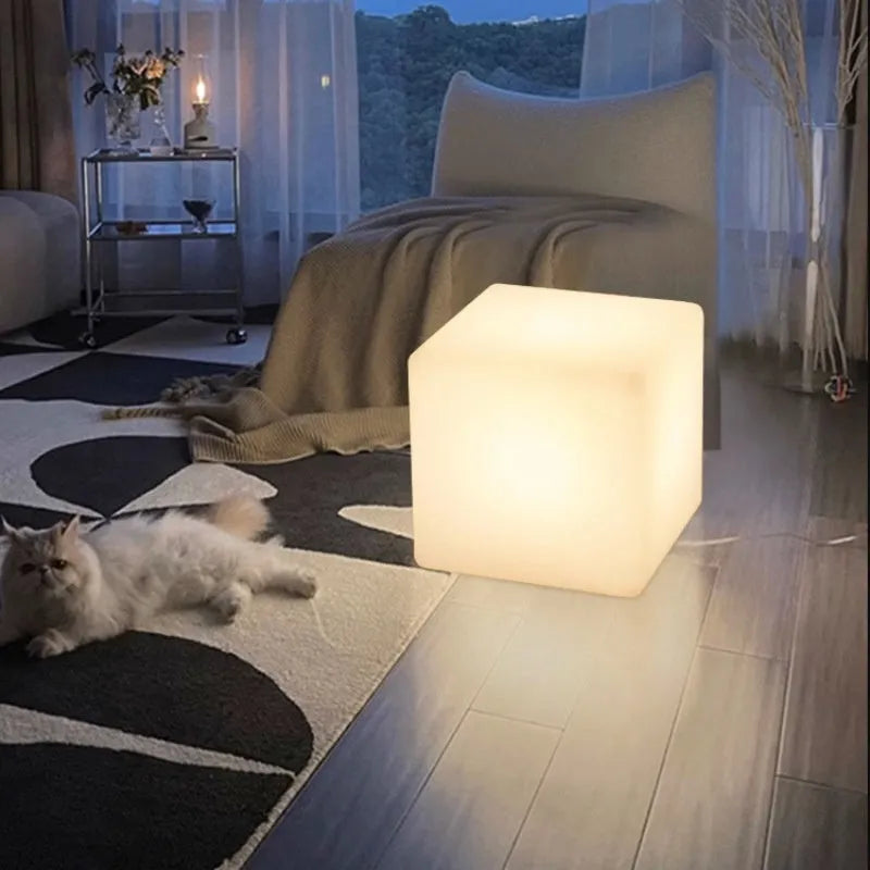White square LED cube stool light on patio, modern outdoor seating with integrated lighting.