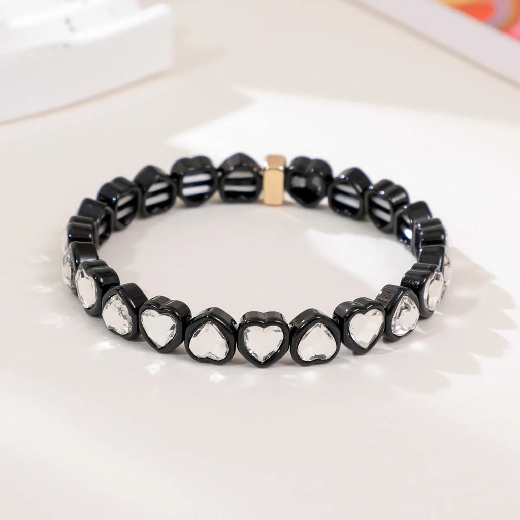 Colourful enamel finish alloy heart charm on a black stretch bracelet band.