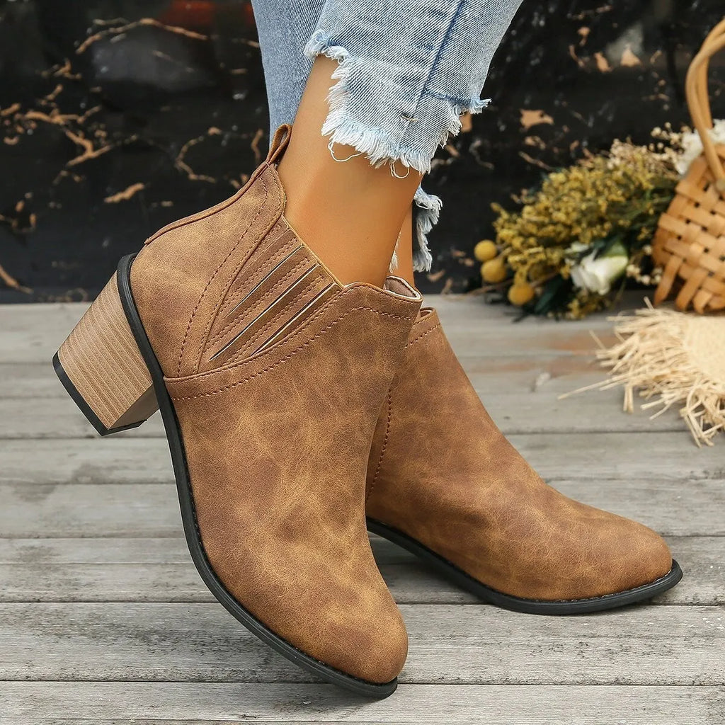 Women's black pointed toe ankle boots with thick square low heel on wooden floor