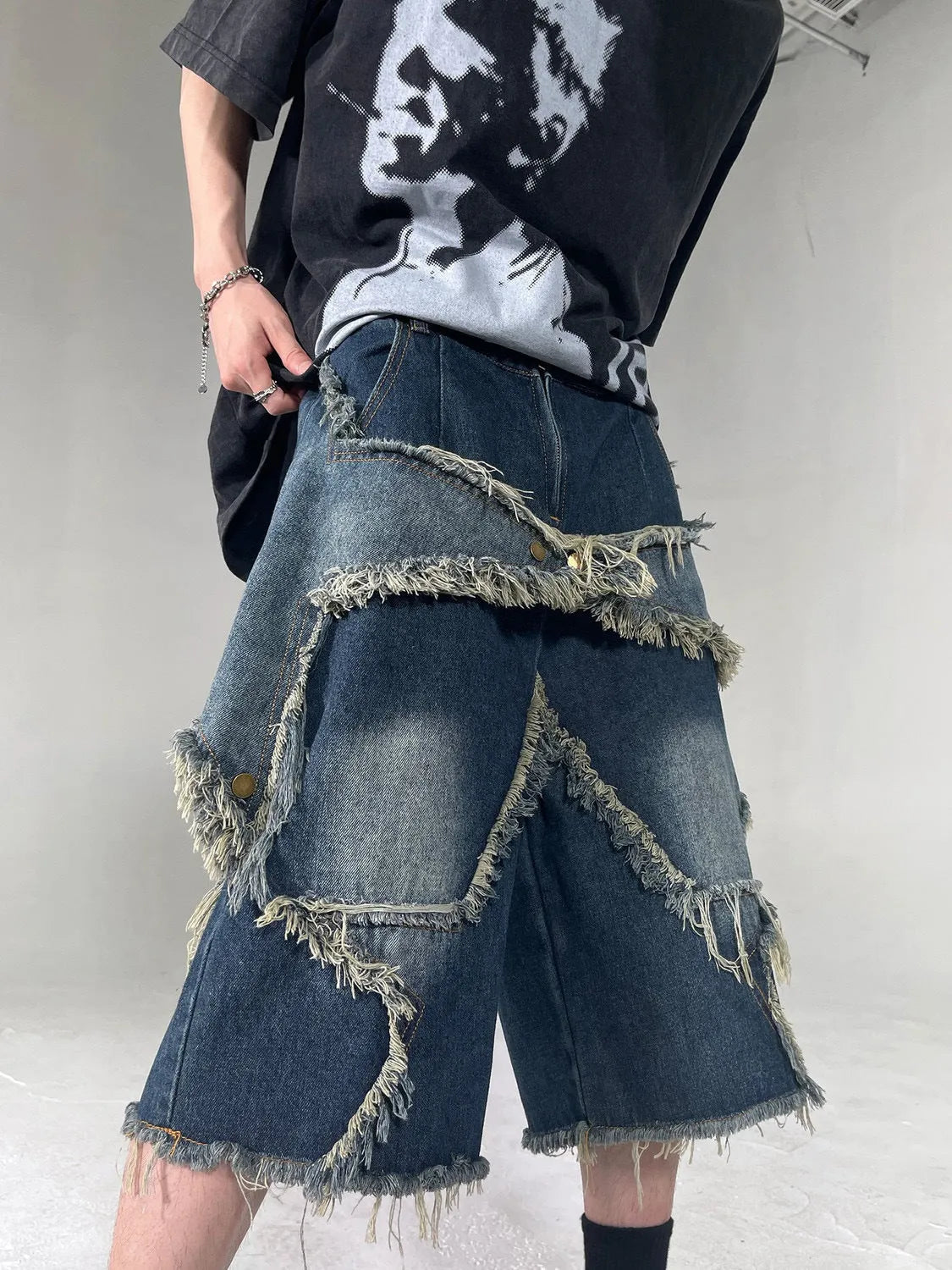 Blue men's denim shorts with a loose fit, frayed hem, and an embroidered five-pointed star on the leg.
