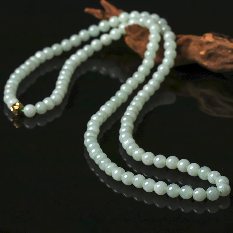 Close-up of a women's adjustable necklace with round white and green natural jade beads on a metal chain.