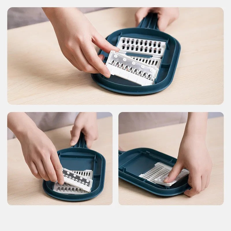 Dark blue vegetable cutter with four stainless steel blades, drain basket, and hand protection guard on kitchen counter