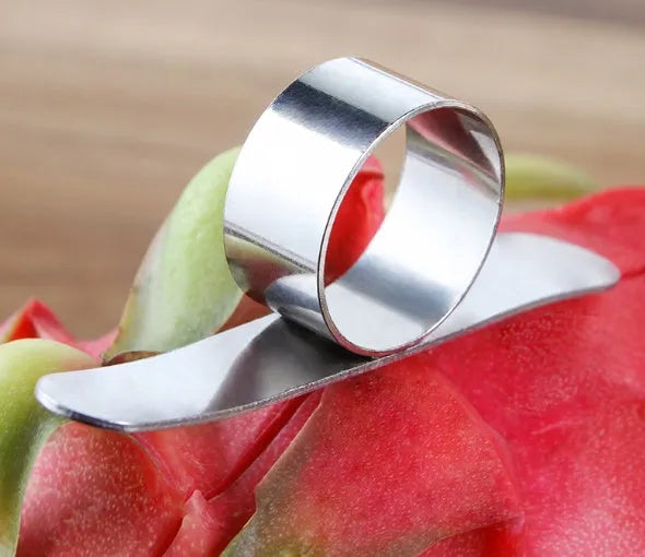 Silver stainless steel finger ring fruit peeler for oranges and pomelos on a kitchen surface.
