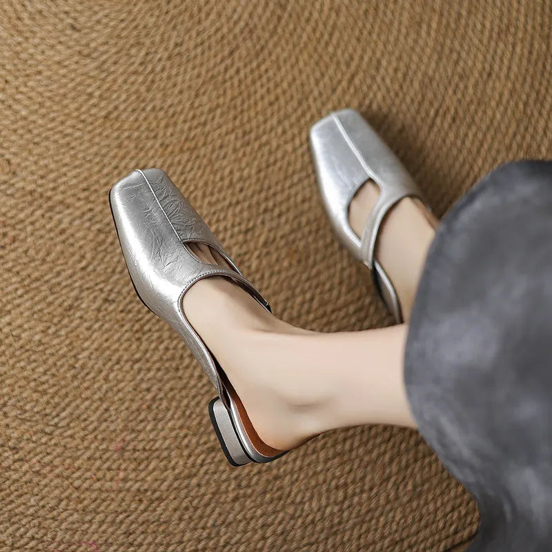 A pair of casual square-toe low-heel slippers in a solid colour on a rubber sole.