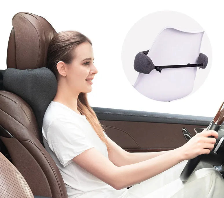 Dark grey memory foam car neck pillow on a car headrest.