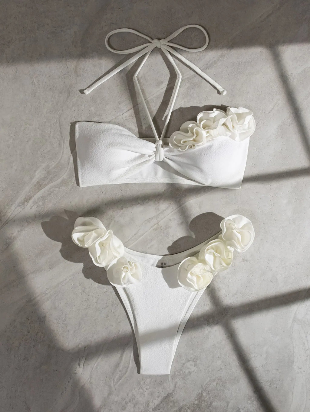 White halter neck lace-up bikini with three-dimensional floral embroidery and brief bottoms.