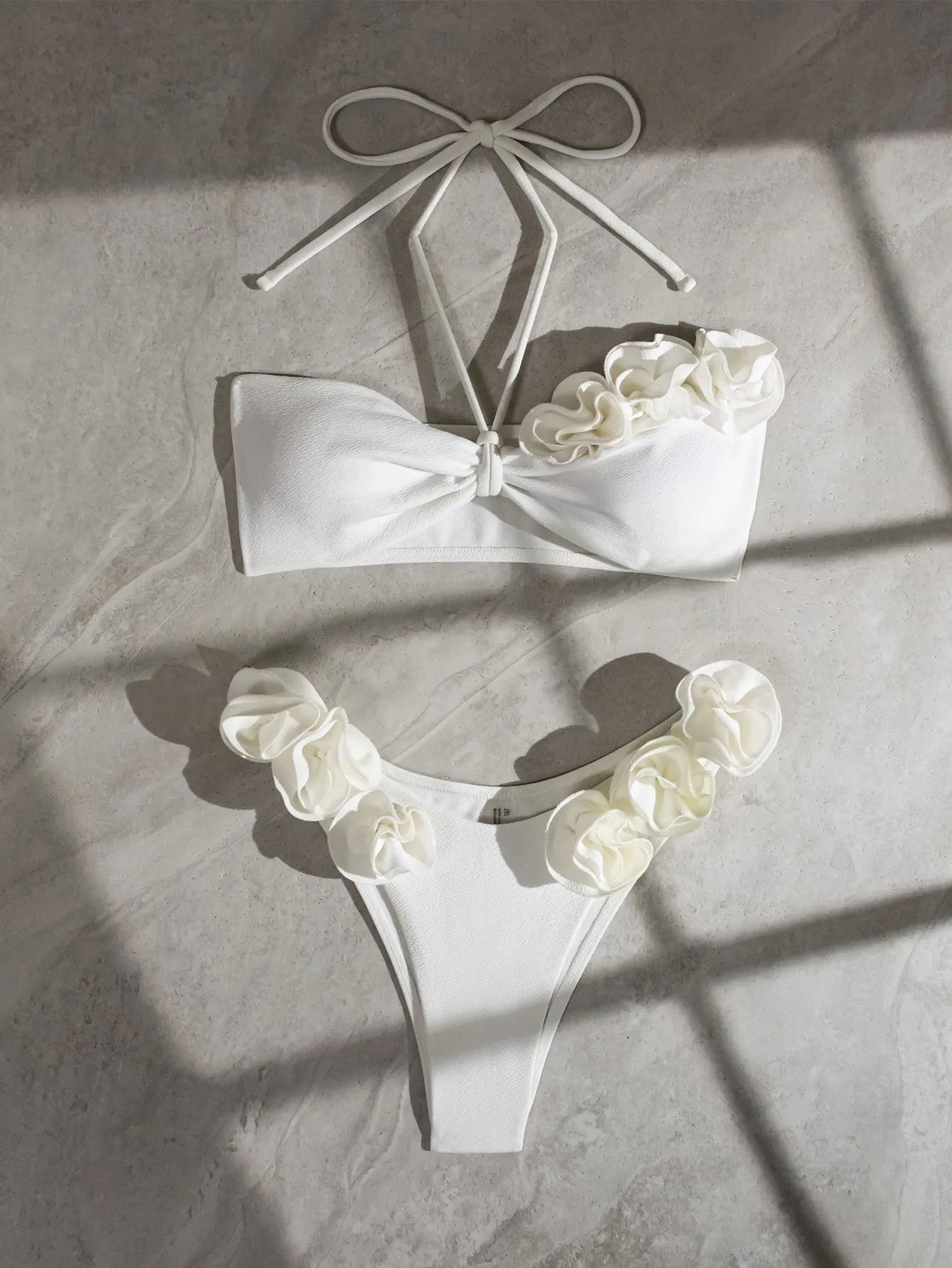 White halter neck lace-up bikini with three-dimensional floral embroidery and brief bottoms.