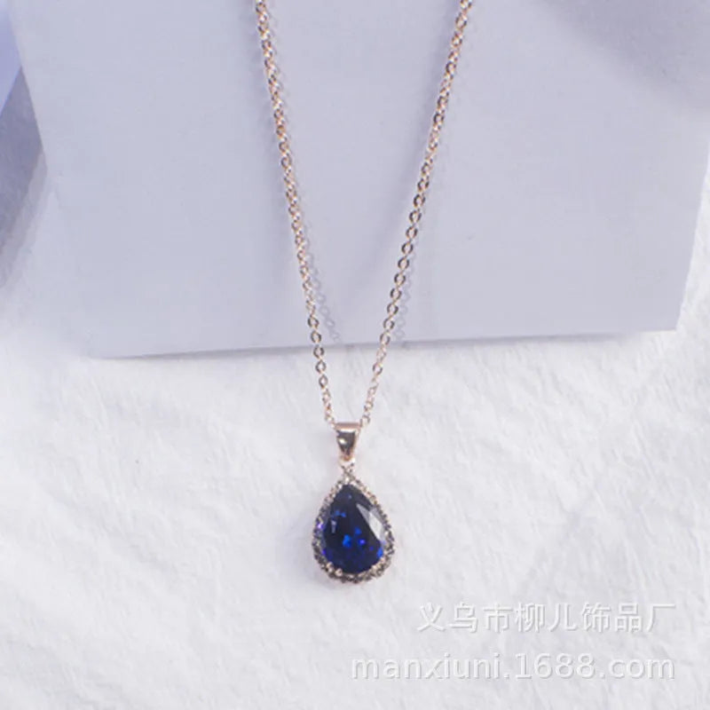 Close-up of a women's rose gold tone drop pendant necklace with pink rhinestone inlay on a model.