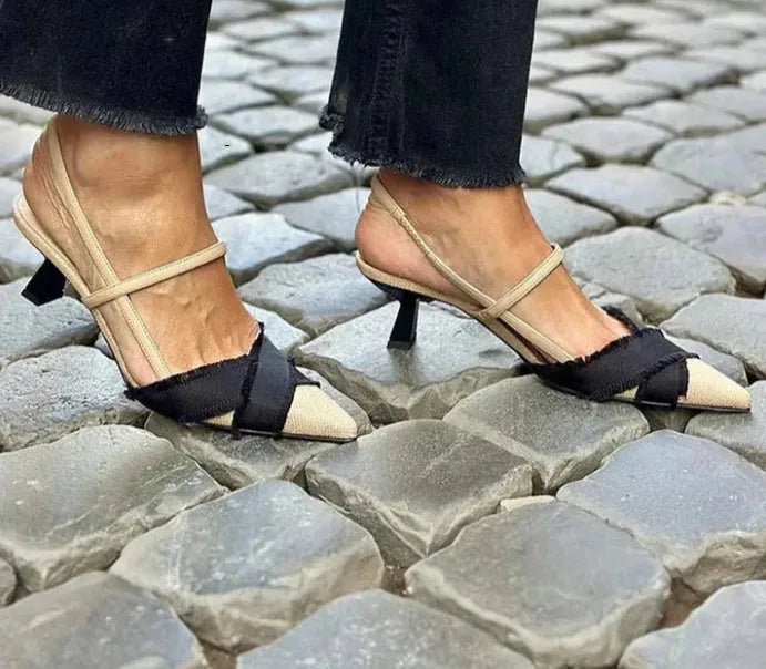 Apricot and black women's stiletto sandals with a pointed toe and buckle fastening on a white background.