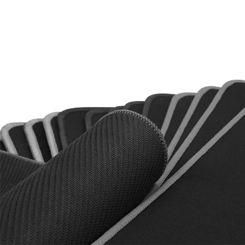Long black desk mat with overlock stitching for keyboard and mouse on a wooden desk.