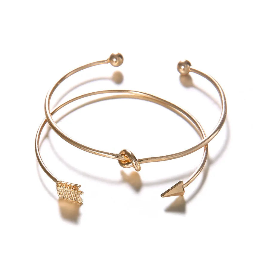 Women's gold vintage cuff bracelet with arrow and knotted design on wrist