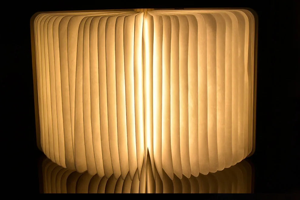 Walnut wooden book light open with colour changing LED pages on a desk