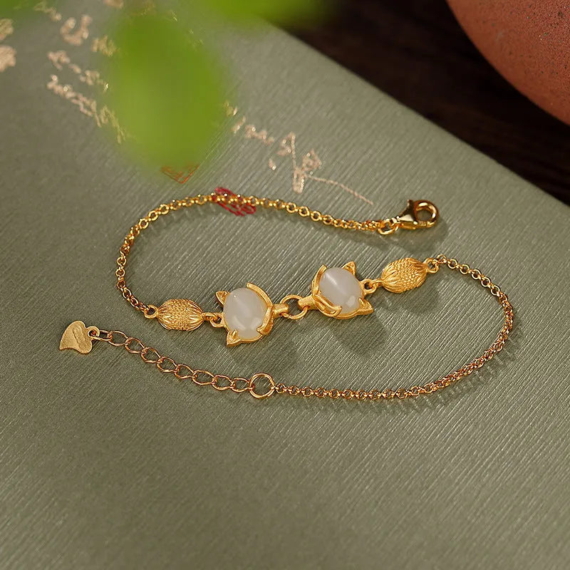 Close-up of a sterling silver fox charm bracelet with a Hetian jade stone on a model's wrist.