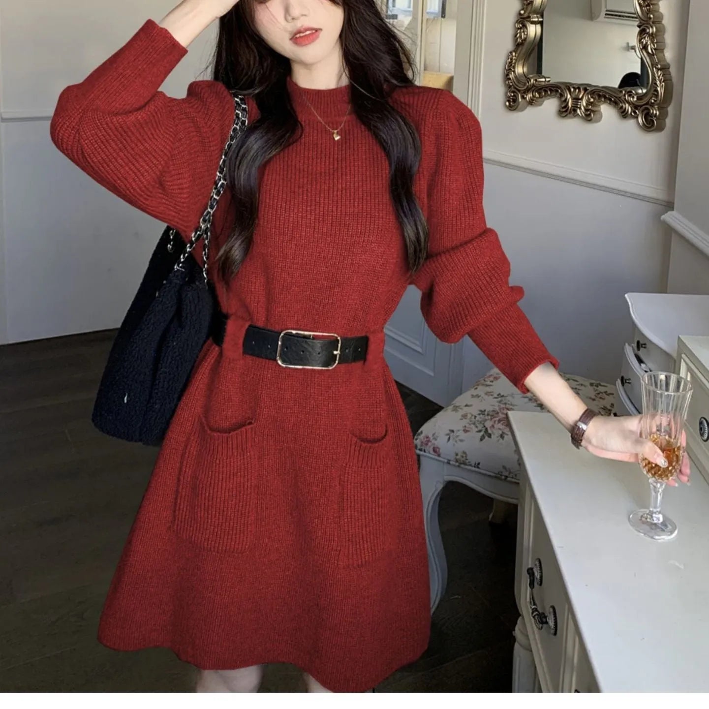 Long sleeve high-waist knitted dress on a hanger with a black belt, shown in beige colour.