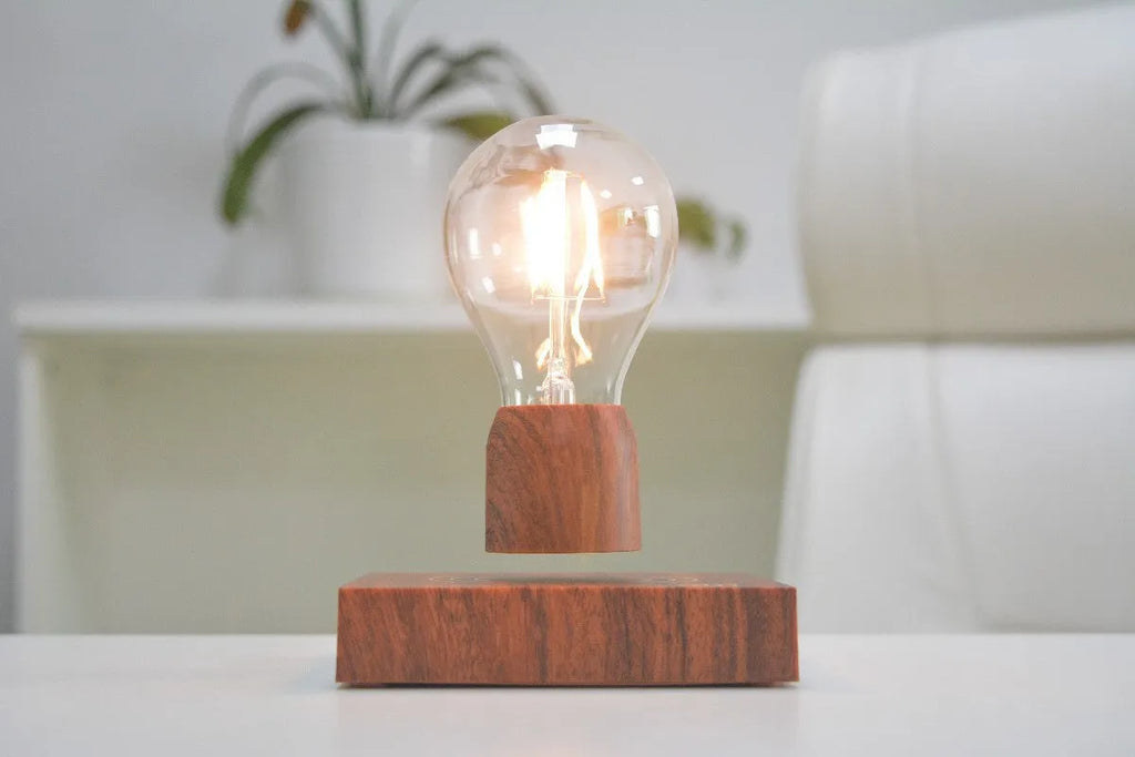 Magnetic levitating light bulb floating above an imitation wood base on a desk.