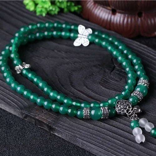 Close-up of a women's multi-strand bracelet with green agate beads on a wrist.