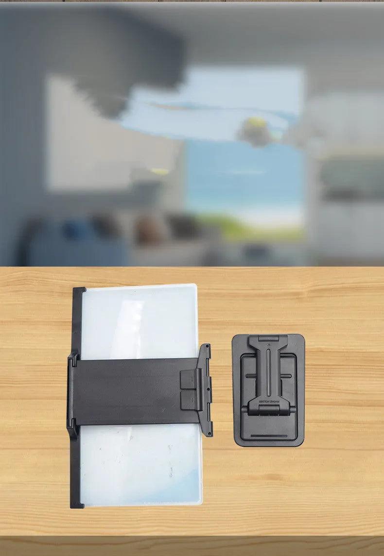Black foldable mobile phone screen magnifier with a detachable phone holder on a desk.