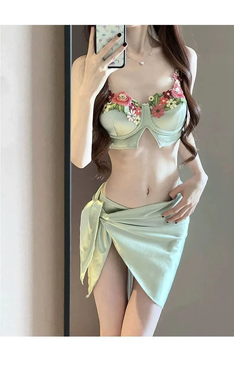 Green three-piece women's bikini swimsuit with triangle top, briefs, and skirt