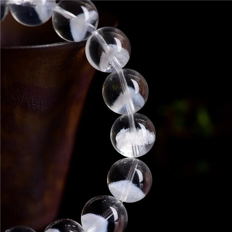 Women's white crystal pyramid bead ghost bracelet with a Ruyi charm on a white background.