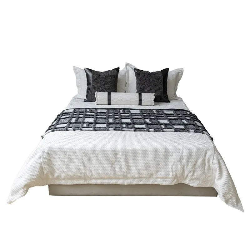 Modern grey and white plaid bed runner blanket set with a matching pillowcase and round pillow on a double bed.