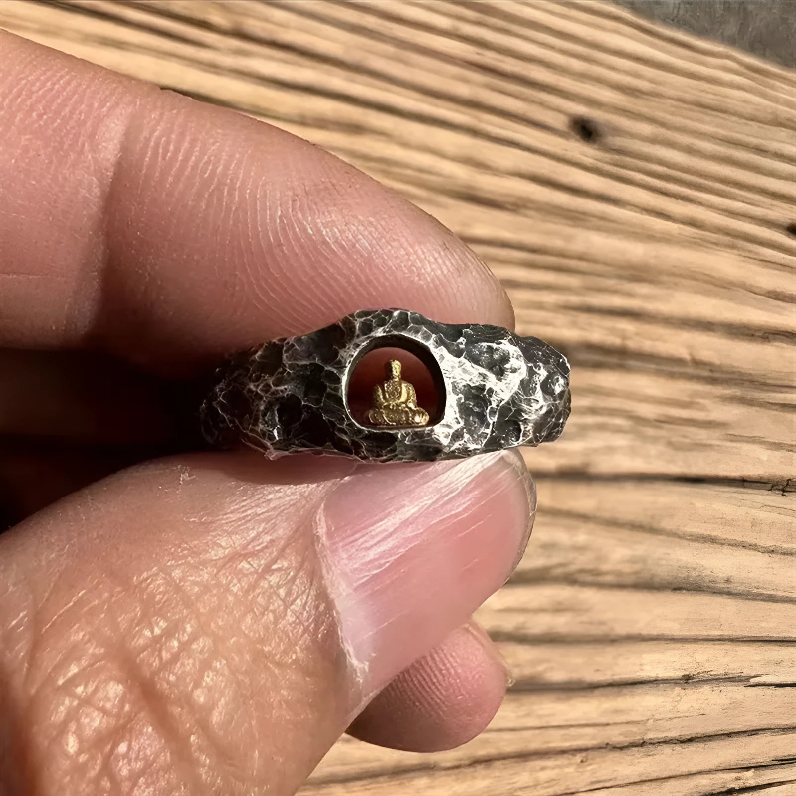 Close-up of a hand-forged copper ring with a textured Grotto Buddha and rock pattern.