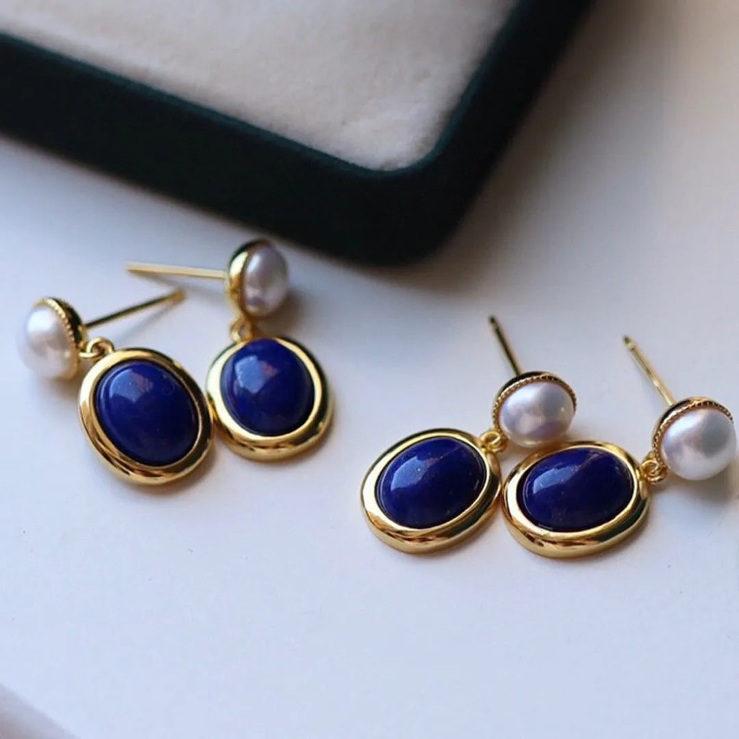 A pair of simple silver earrings with blue lapis lazuli pearls and auspicious pattern details.