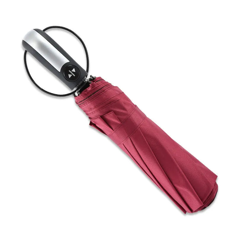A folded black automatic business umbrella with a rubber handle, showing its triple folding design.