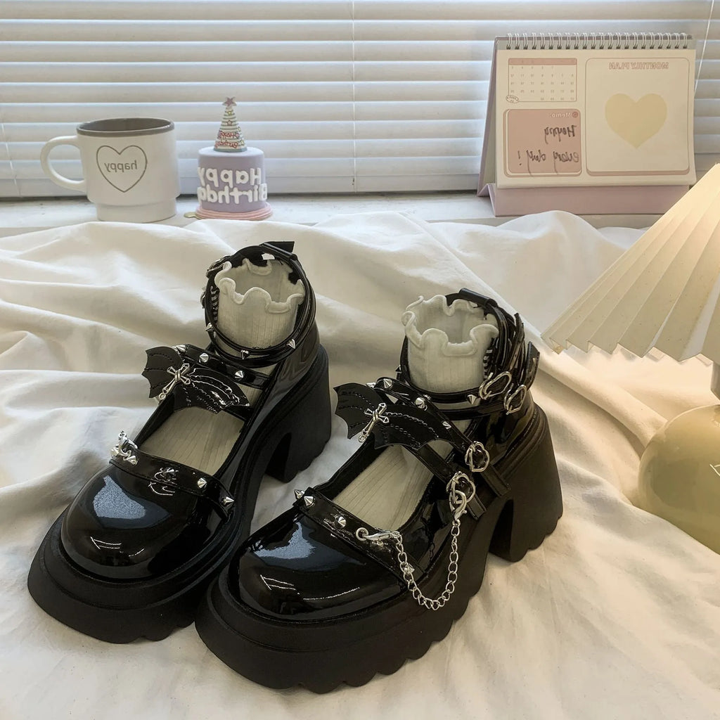 Black patent leather bat cosplay Lolita shoes with metal chain buckle and chunky heel on white background