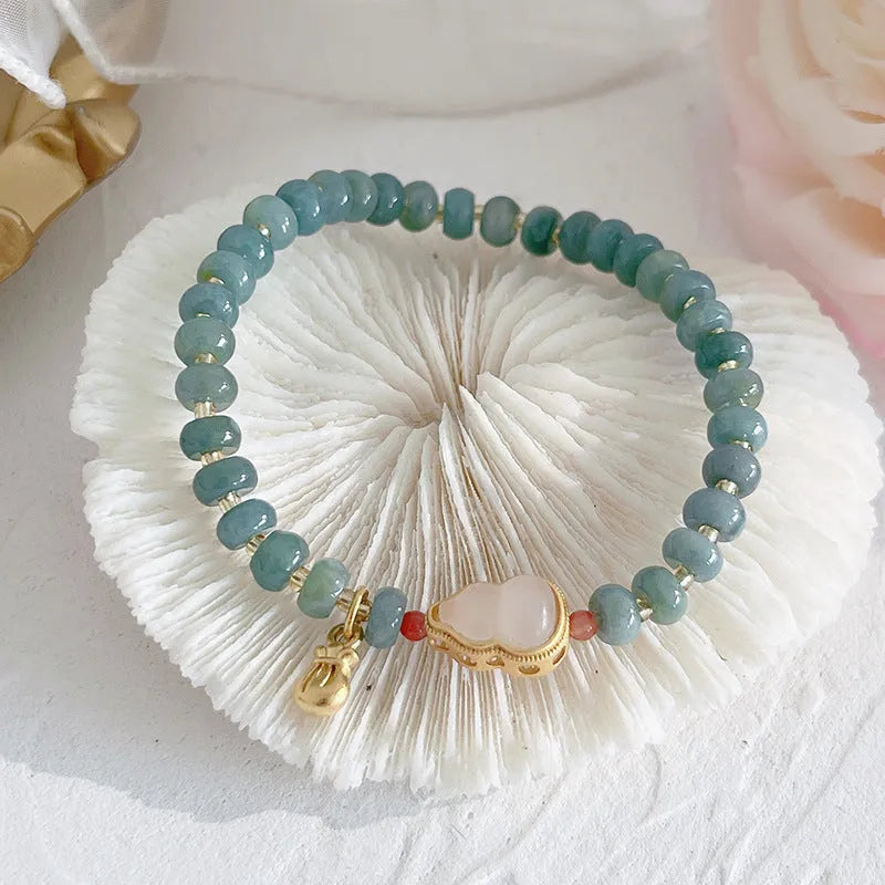 Blue-toned jade bracelet with gourd and peace buckle charms and strawberry quartz accents