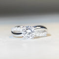 Geometric twisted silver band ring with 1 karat moissanite stone in four-claw setting, side view showing cross details