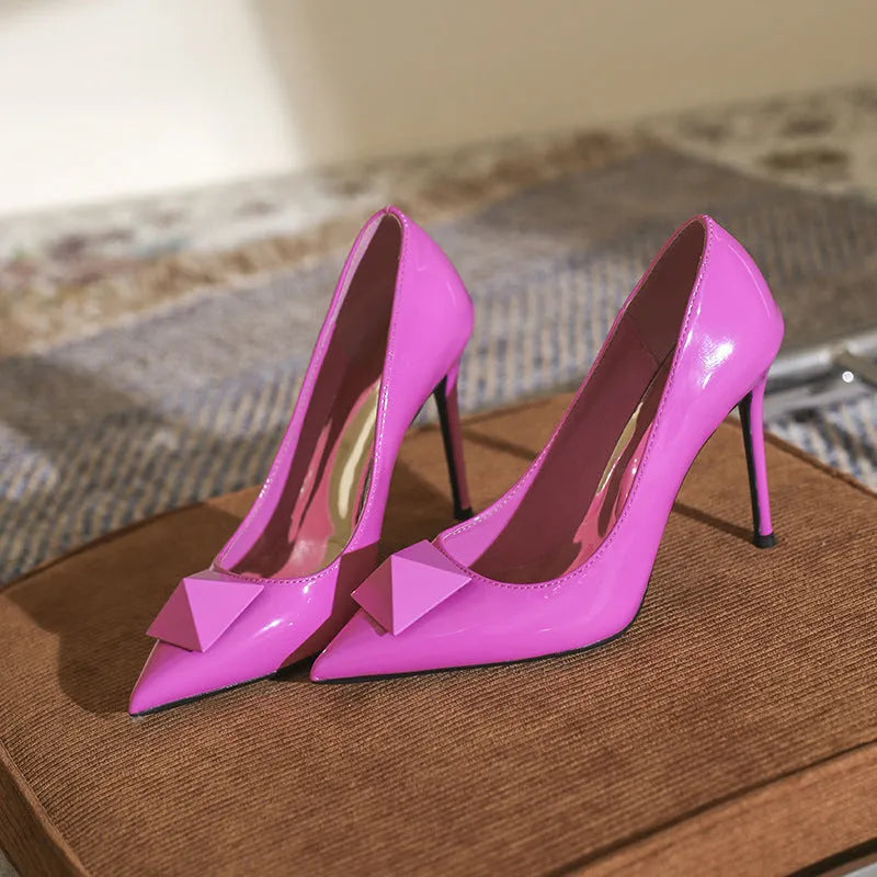 Pink patent leather women's stiletto heels with pointed toe, rivet details, and a buckle ankle strap.