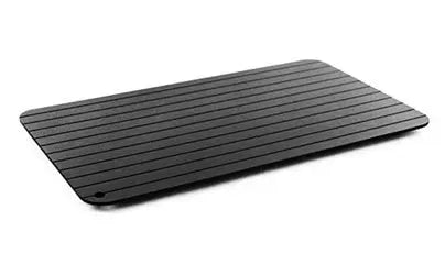 Black aluminium quick defrosting tray for thawing meat and frozen food on a kitchen counter.