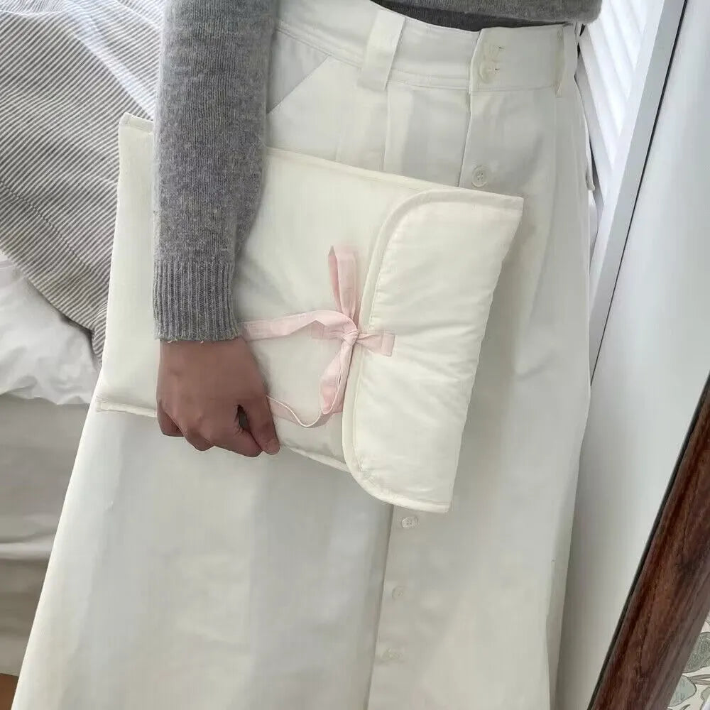 Women's black and white striped quilted laptop bag with a large ballet-style bow on the front.