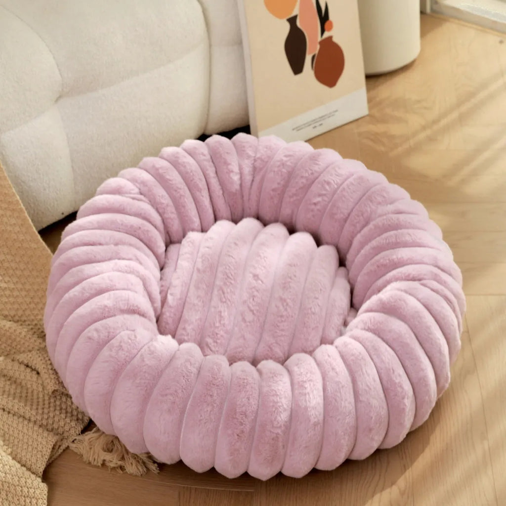 A round, plush beige pet nest bed for cats or dogs on a wooden floor.