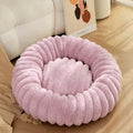 A round, plush beige pet nest bed for cats or dogs on a wooden floor.