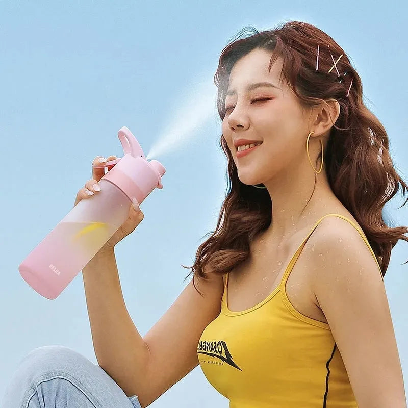 White 700ml plastic spray water bottle with a black handle strap and leakproof lid on a table.