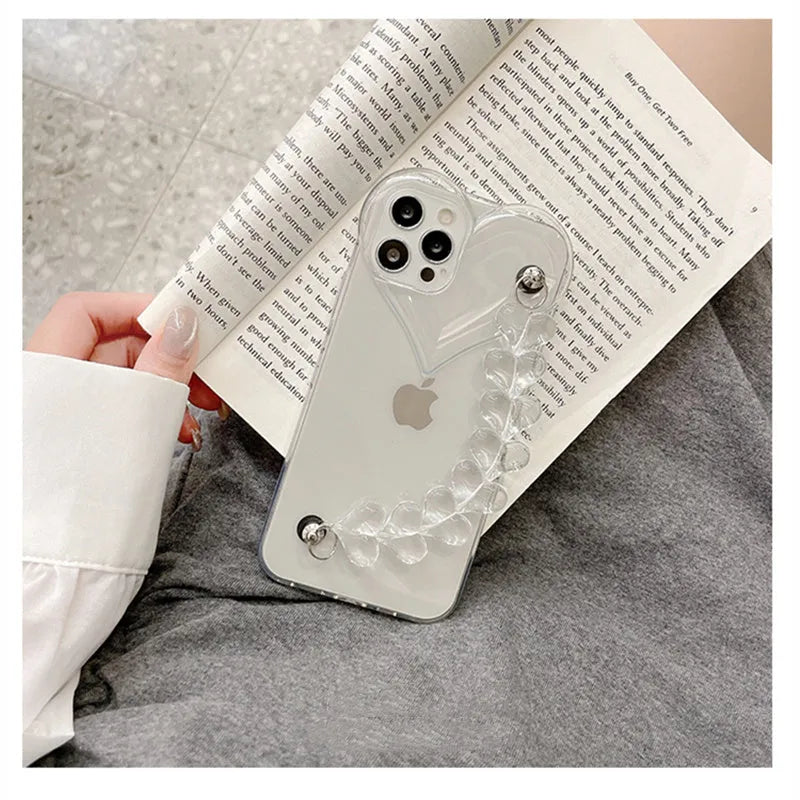 Transparent iPhone case with a love heart charm on a chain, on an iPhone.