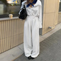 White wide-leg trousers with vertical stripes, featuring a loose casual fit and a front zipper fastening.