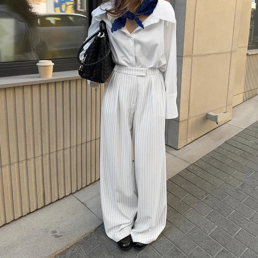 White wide-leg trousers with vertical stripes, featuring a loose casual fit and a front zipper fastening.