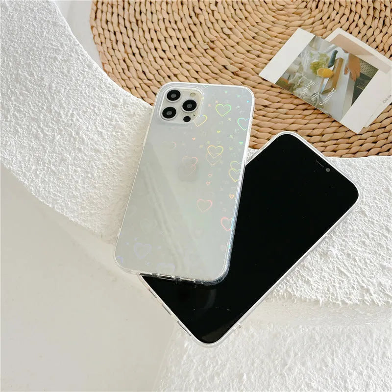 Transparent silicone iPhone case with a colourful laser love heart pattern on a table.