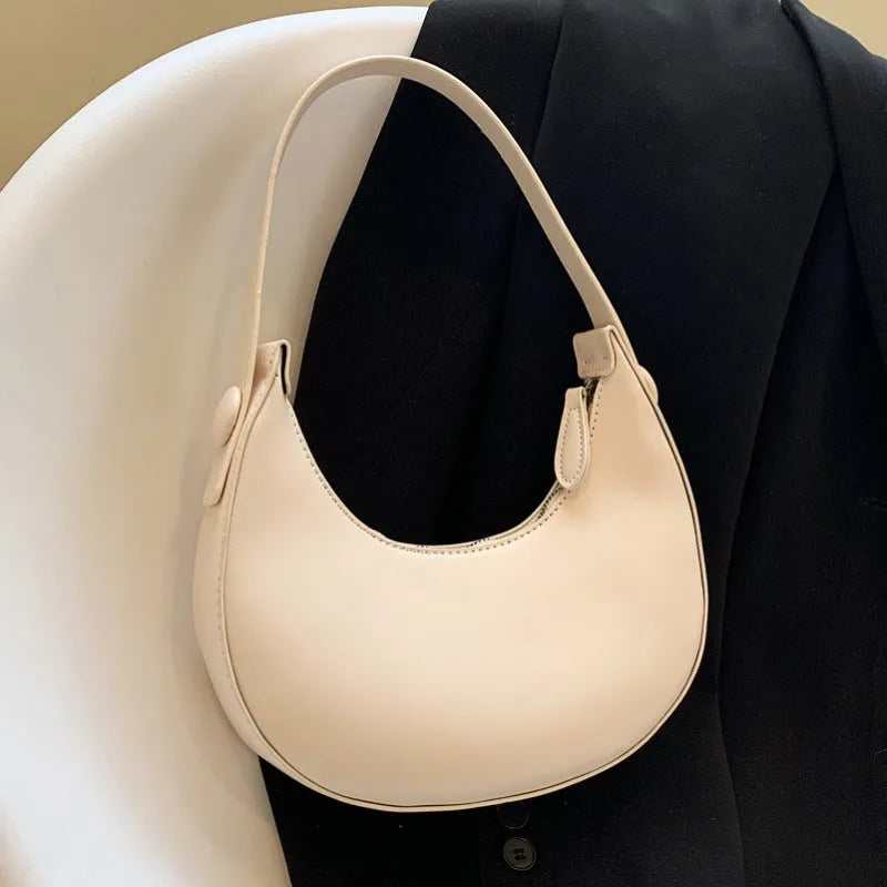 Women's retro-style PU dumpling shoulder bag in black, showing front zipper compartment.
