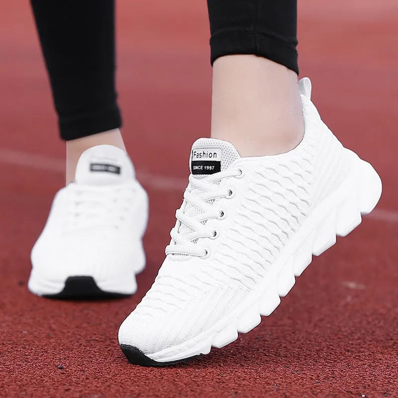 Women's black and pink running shoes showing fly weave upper texture and rubber outsole.
